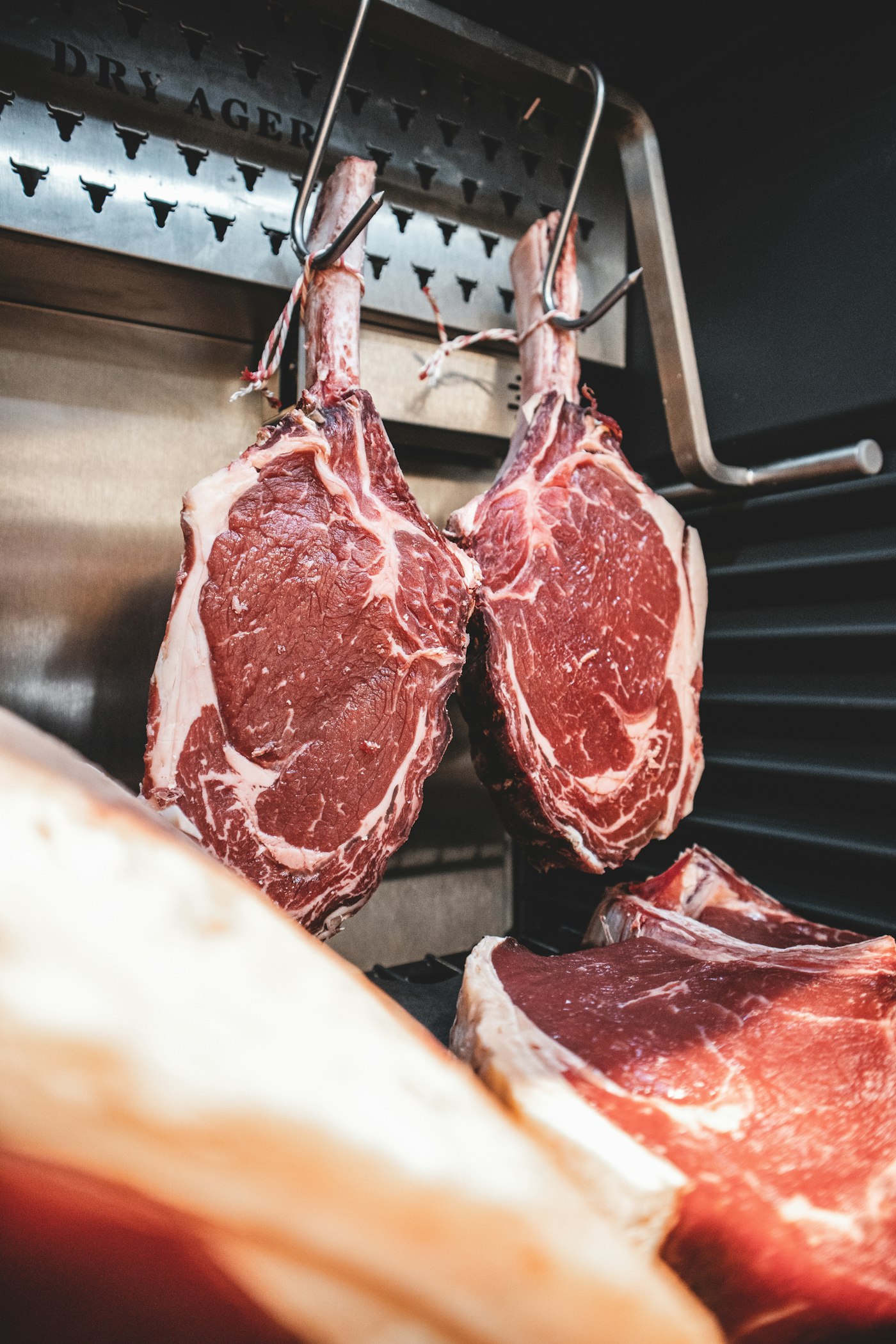 Bone-in rib steaks hanging to age in a cold room