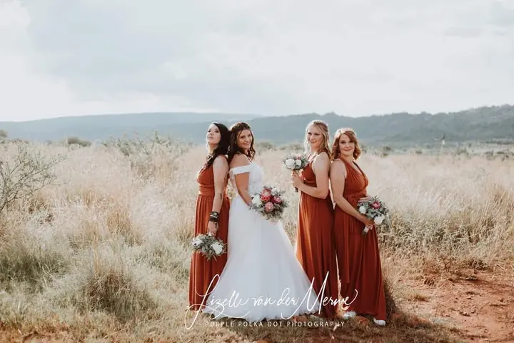 Bride and bridesmaids in rust dresses in the veld
