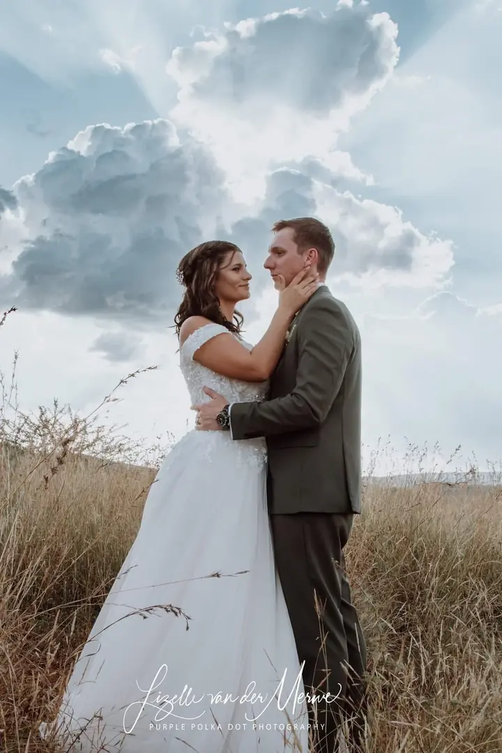 Newlyweds embracing under a wide sky