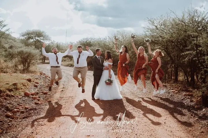 A wedding party walking along a red dirt road