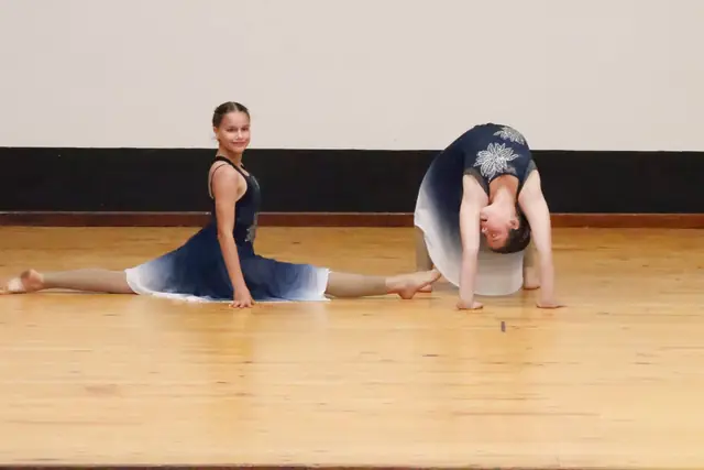 Two dancers in blue, one in a split and one in a backbend.