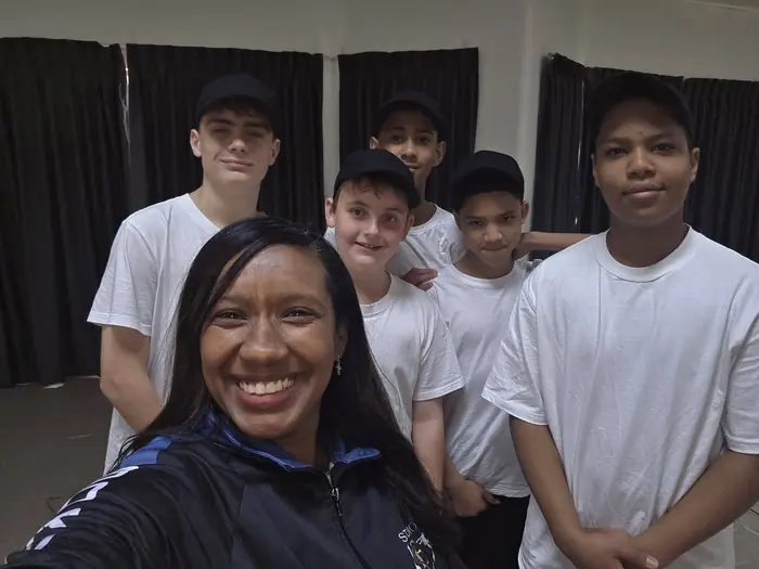 Dance teacher Suné Jameson smiling in a selfie with the boys' crew behind her.