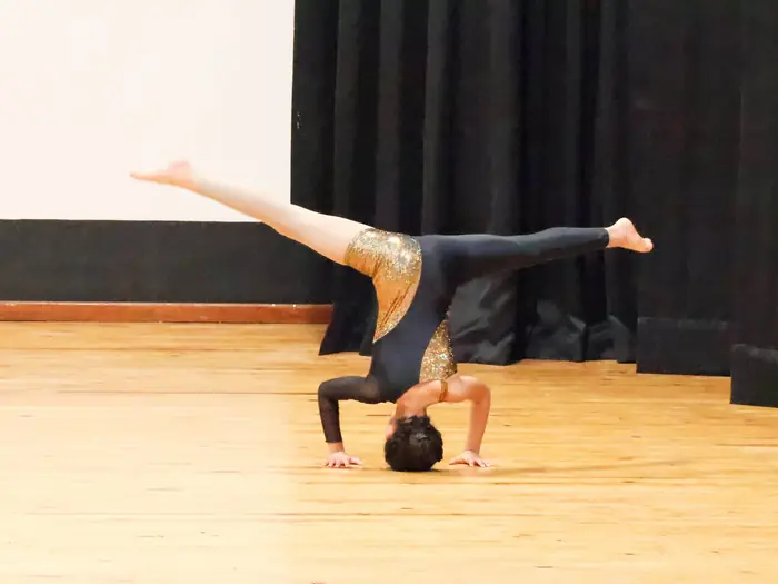 A dancer in a forearm stand with her legs split wide on stage.