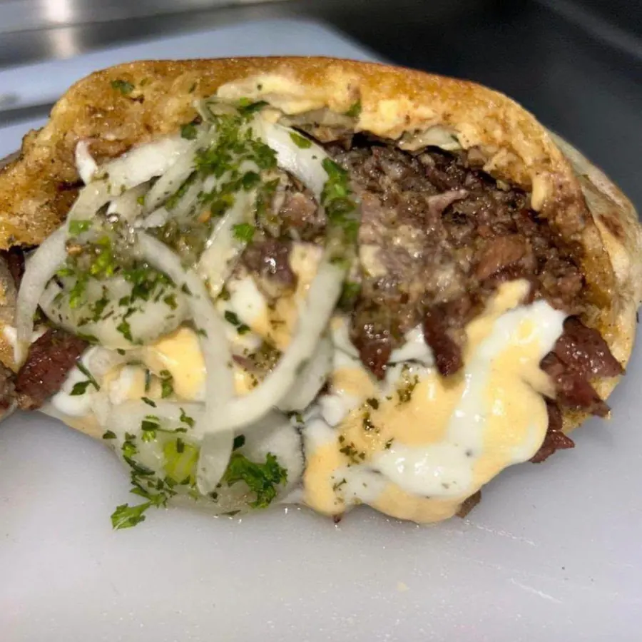 A pita pocket shawarma filled with grilled beef, onions, parsley and cheese sauce