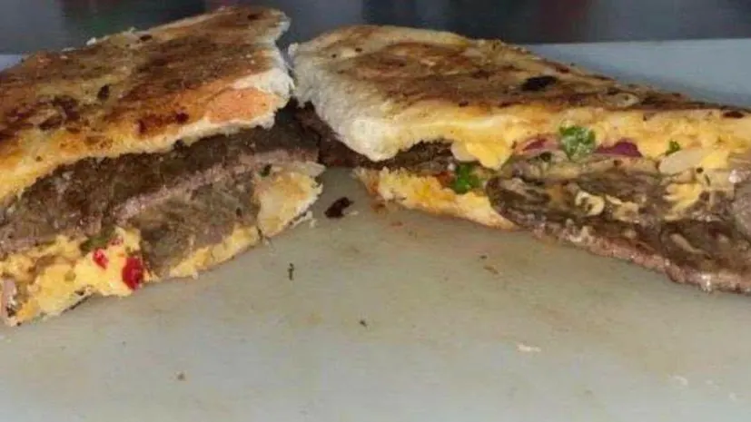 A toasted cheesy steak roll cut open to show steak and melted cheese