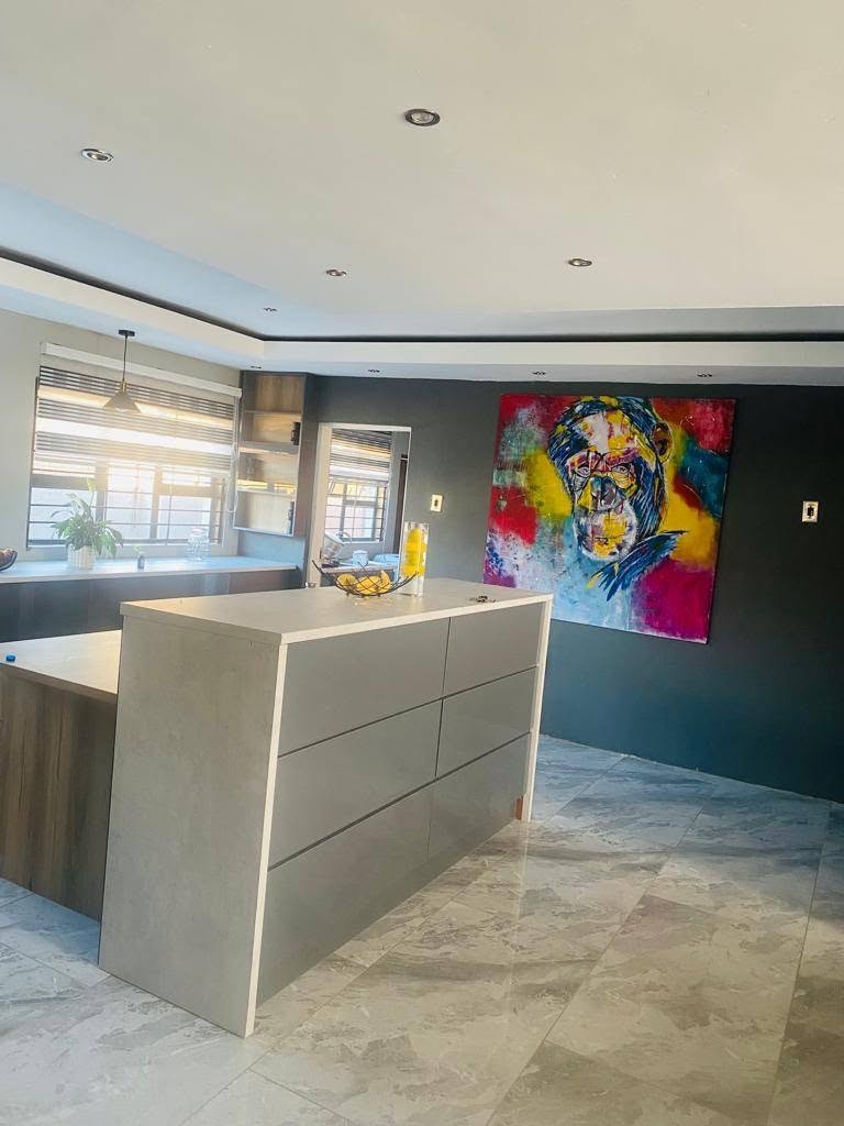The colourful primate painting hanging on a dark slate wall in a modern kitchen